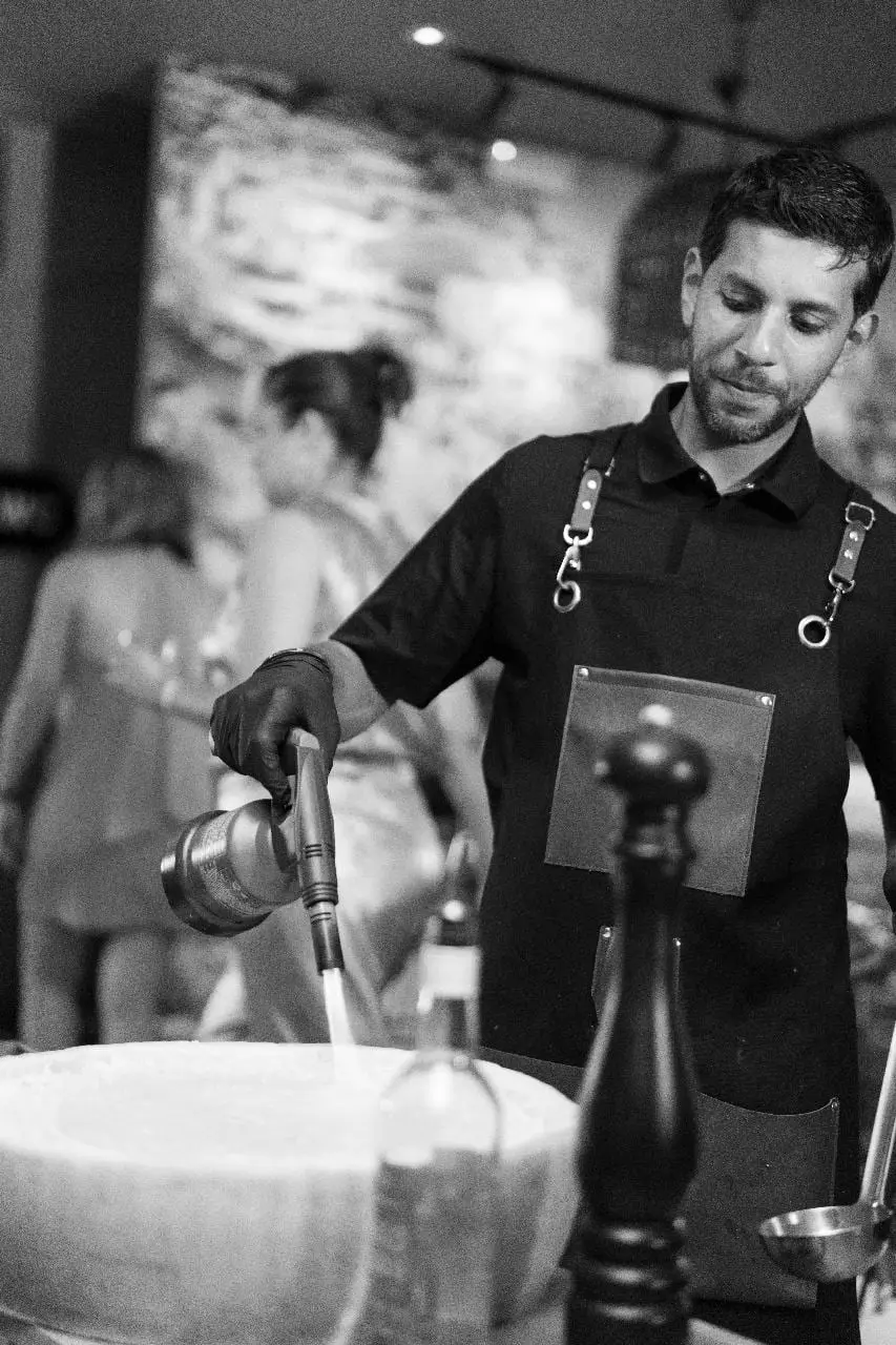 Our chef at the Parmigiano wheel during a live cooking service